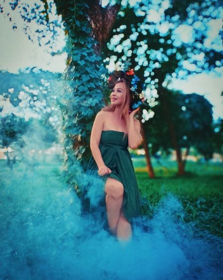 Smiling woman looking away while standing by smoke on field