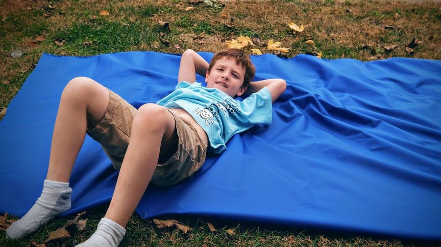 High angle view of boy lying on blanket at filed