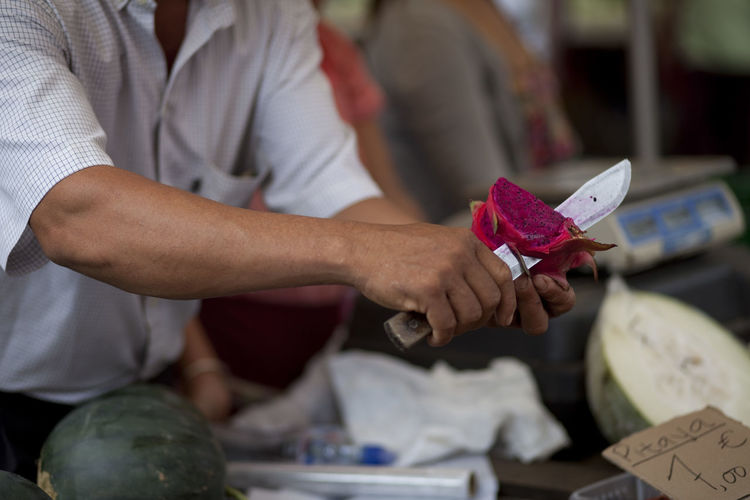 Midsection of market vendor cutting pitaya