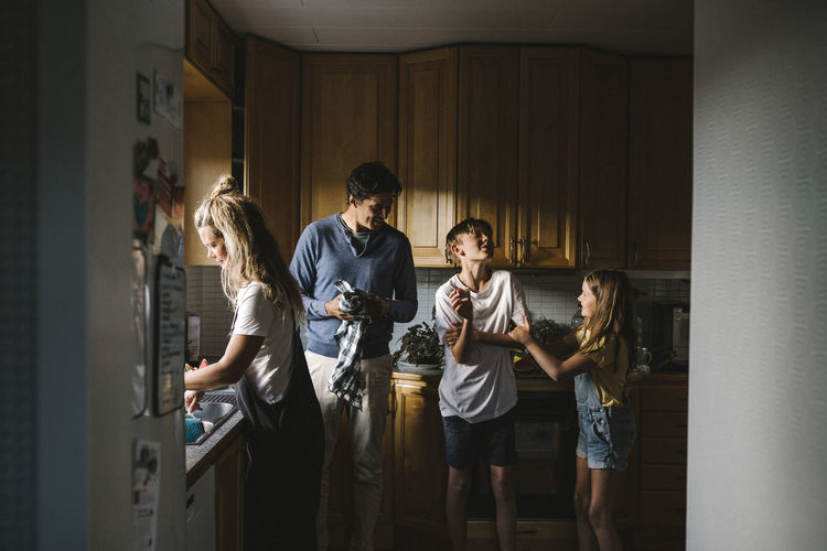 Siblings with parents standing in kitchen