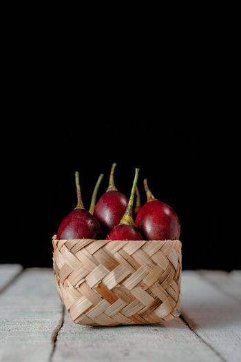 Close-up of apples in basket on table against black background