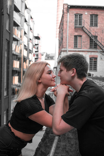 Young couple standing by buildings in city