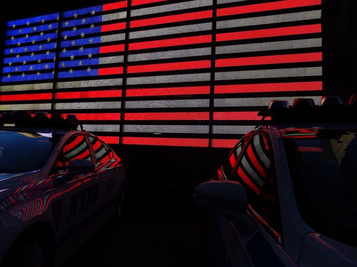 Police cars against illuminated american flag on wall