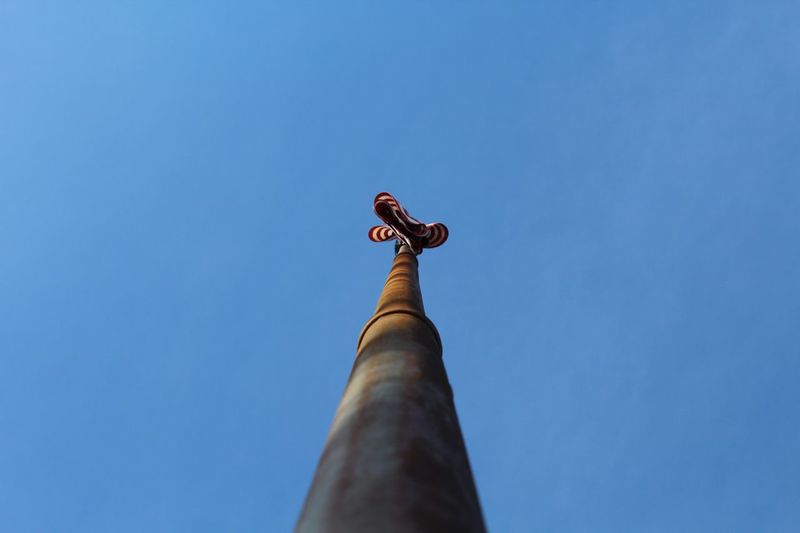 Directly below of flag pole against clear blue sky