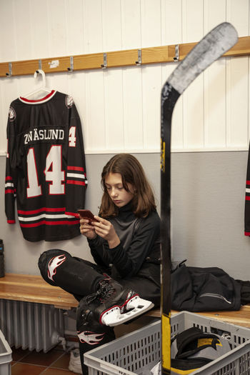 Girl hockey player using cell phone in locker room