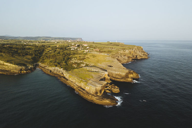Rugged cliff coastline by the seaside, near a lighthouse in cantabria, spain
