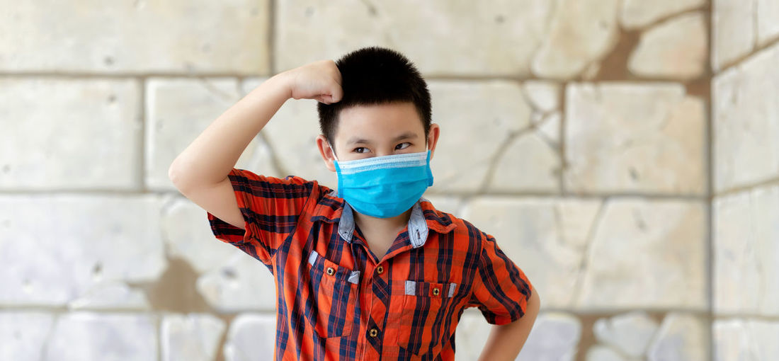 Portrait of boy standing against wall
