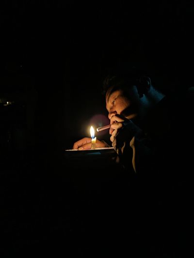 Man holding lit candle in darkroom
