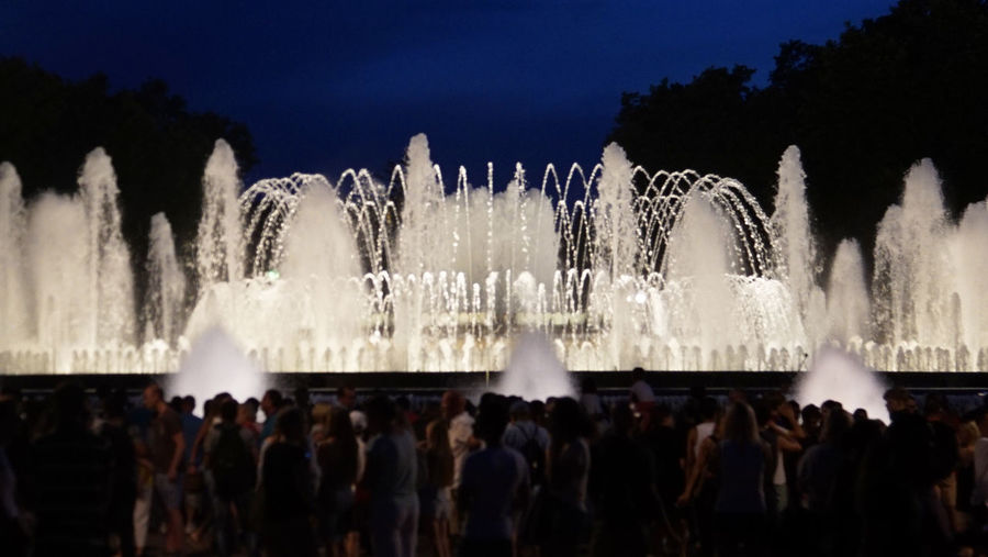 Panoramic shot of silhouette people at fountain against sky at night
