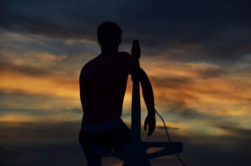 Silhouette man standing against sea during sunset