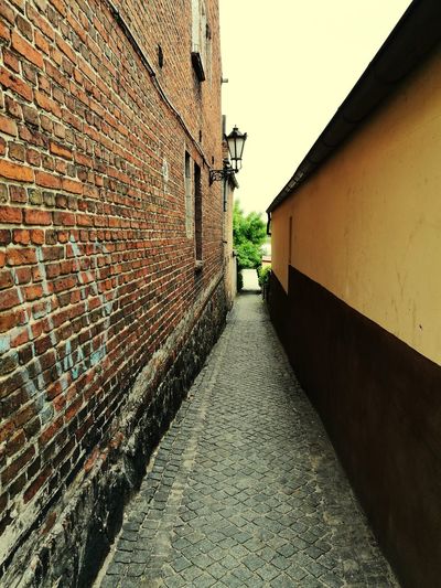 Cobblestone street in city against clear sky