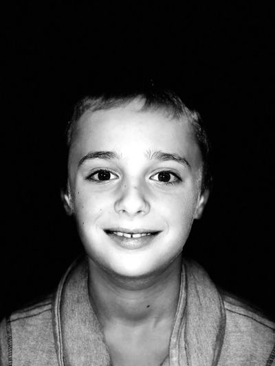 Portrait of smiling boy against black background