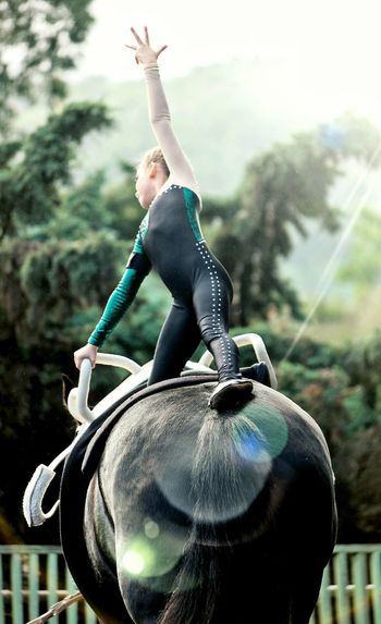 Girl performing equestrian vaulting on black horse