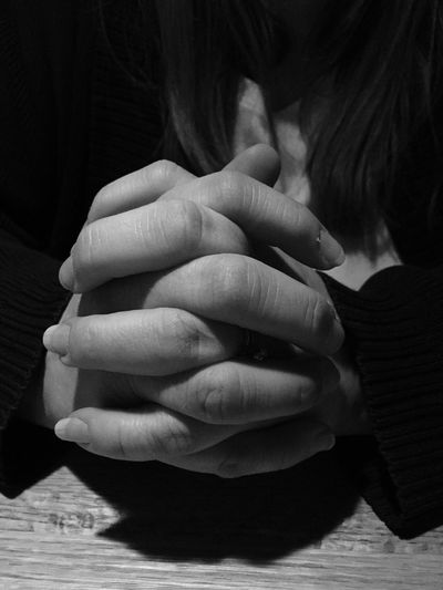 Close-up of hands clasped on table at home