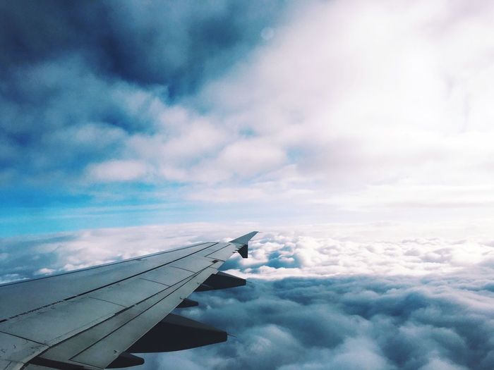 Cropped image airplane flying over cloudscape against sky