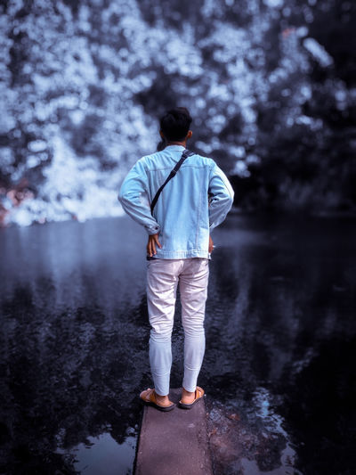 Rear view of man standing by lake