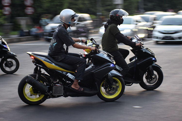 People riding motor scooter on road