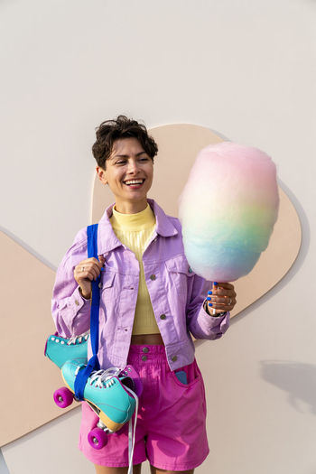Portrait of smiling young woman with balloons against wall