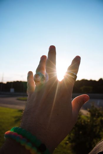 Cropped image of hands wearing rings and bracelet against sky