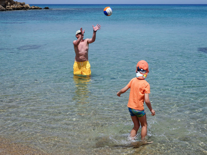 Man with son playing volleyball in sea
