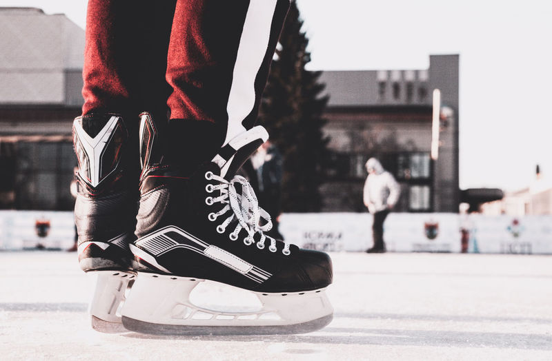 Low section of man wearing ice skates standing at skate park