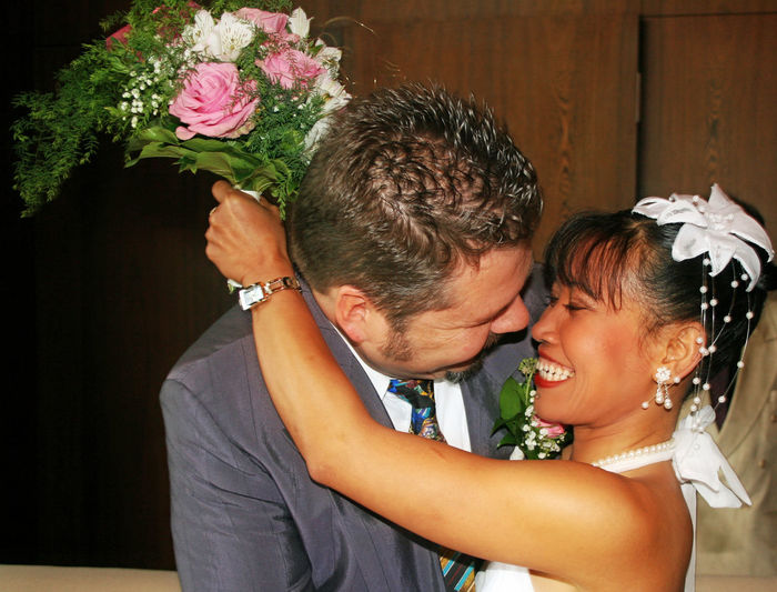 Close-up of smiling couple with bouquet romancing during wedding ceremony