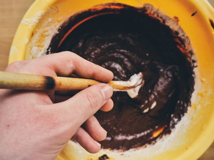 Cropped image of hand stirring chocolate cake batter in container