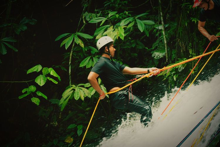 Side view of man rappelling on waterfall