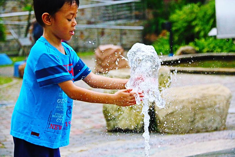 Boy playing fountain at water park