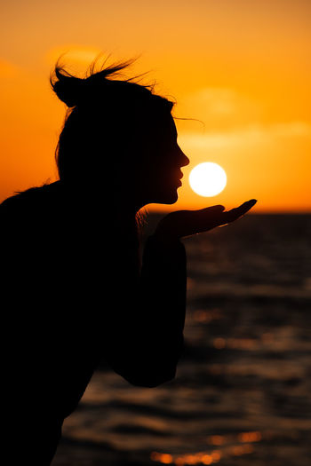 Silhouette woman against sea during sunset