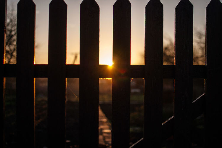 Wooden fence against sky during sunset