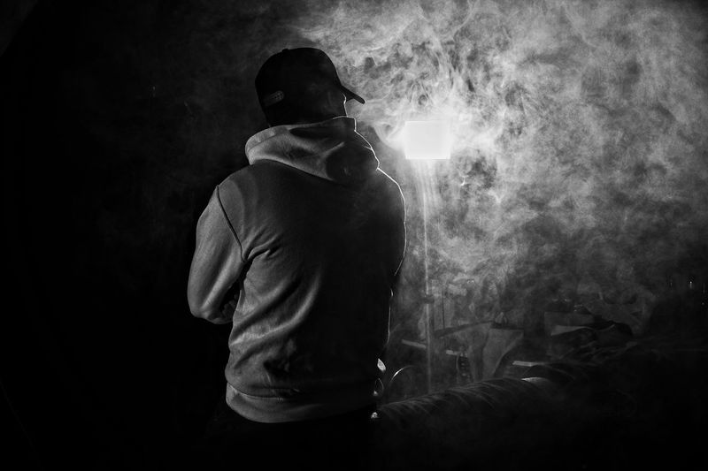 Rear view of man standing against illuminated lighting equipment