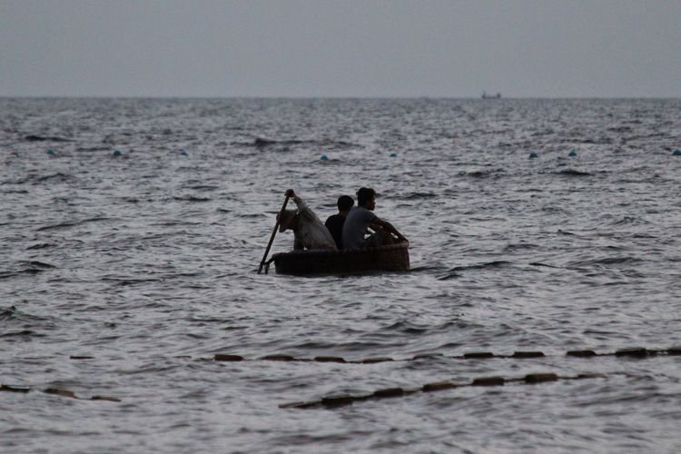 People in boat on sea against clear sky