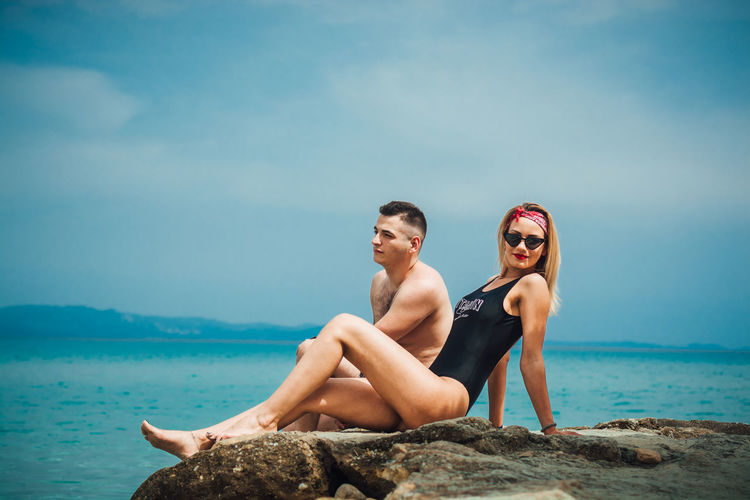 Young couple spending leisure time at beach against sky
