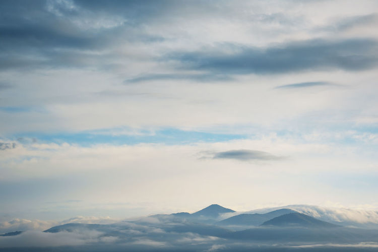 Scenery of clouds around mountain range and overcast sky