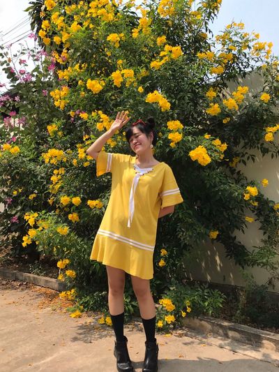 Full length of woman standing by yellow flowering plants