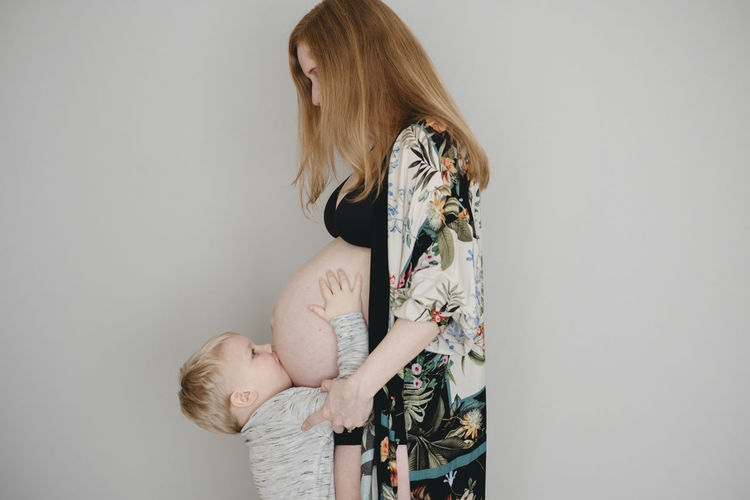 Boy kissing mothers belly