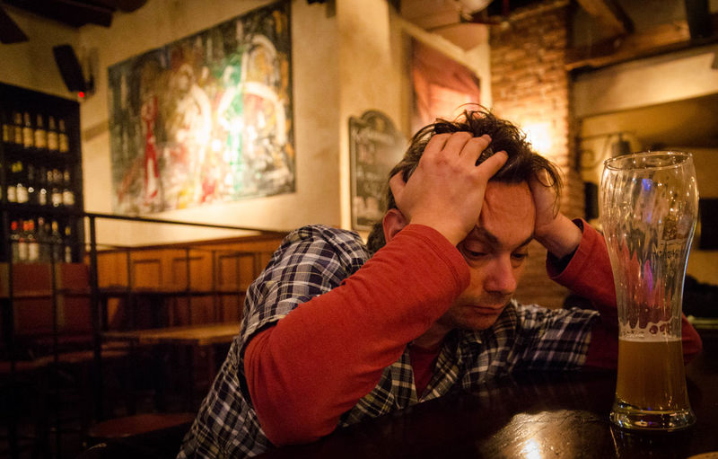 Drunk man sitting at table in bar