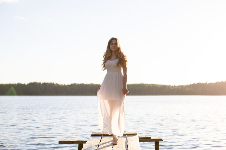 Portrait of young woman standing by lake