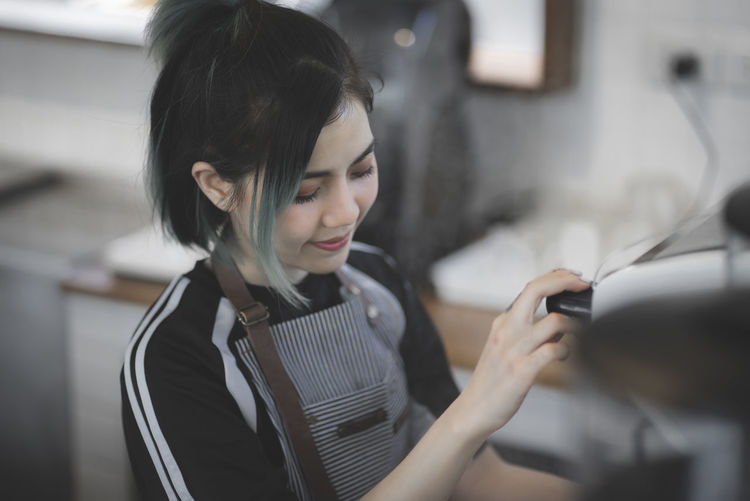 Smiling barista making coffee at cafe