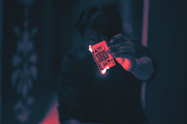 Close-up of man holding burning playing card