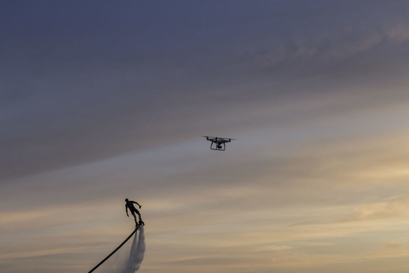 Low angle view of man flyboarding against sky