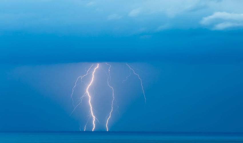 Lightning over sea against blue sky