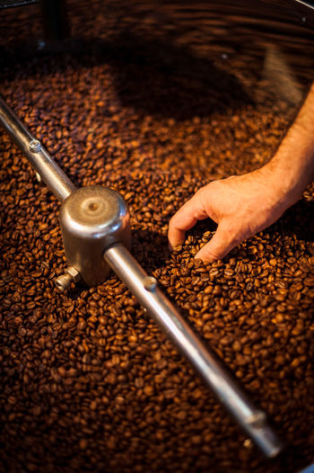 Cropped image of man grinding coffee beans on espresso maker at cafe