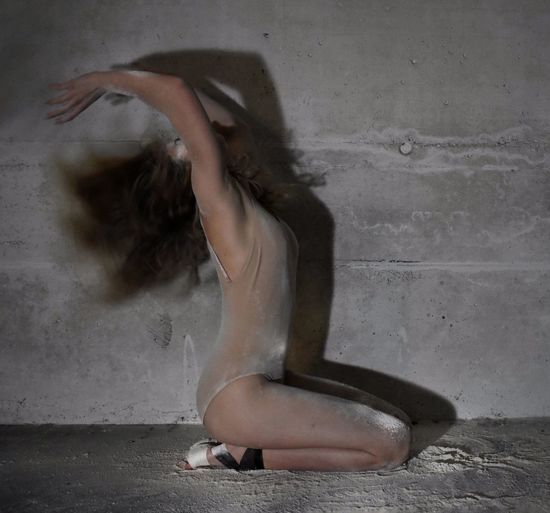 Ballet dancer dancing against wall