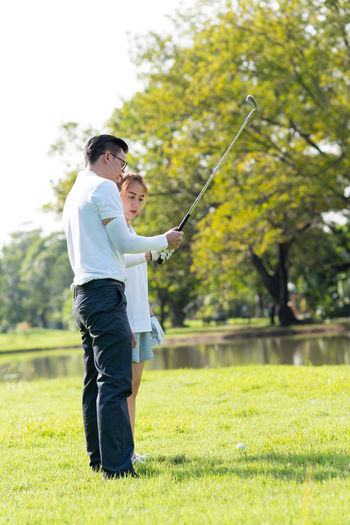 Full length of couple playing golf on field
