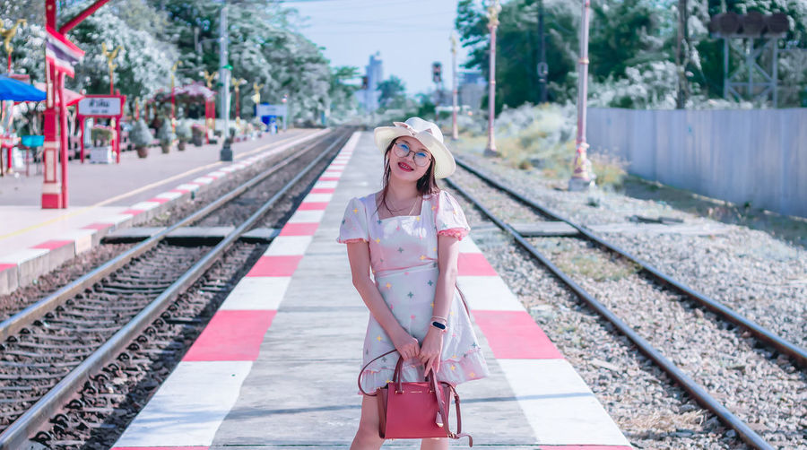 Portrait of smiling woman standing on railroad station platform
