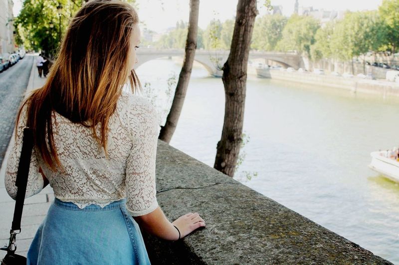 Rear view of young woman standing on promenade by seine river