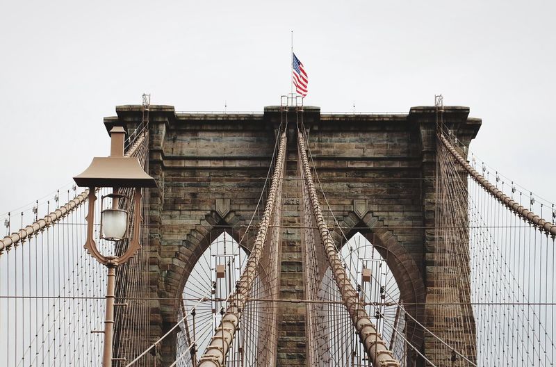 Suspension bridge in city against cloudy sky