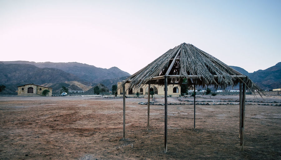 Built structure on field by mountains against clear sky